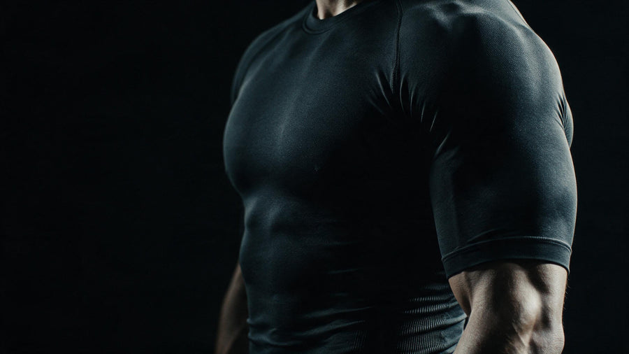 Torse en haut de compression noir, lumière latérale sculptant la matière